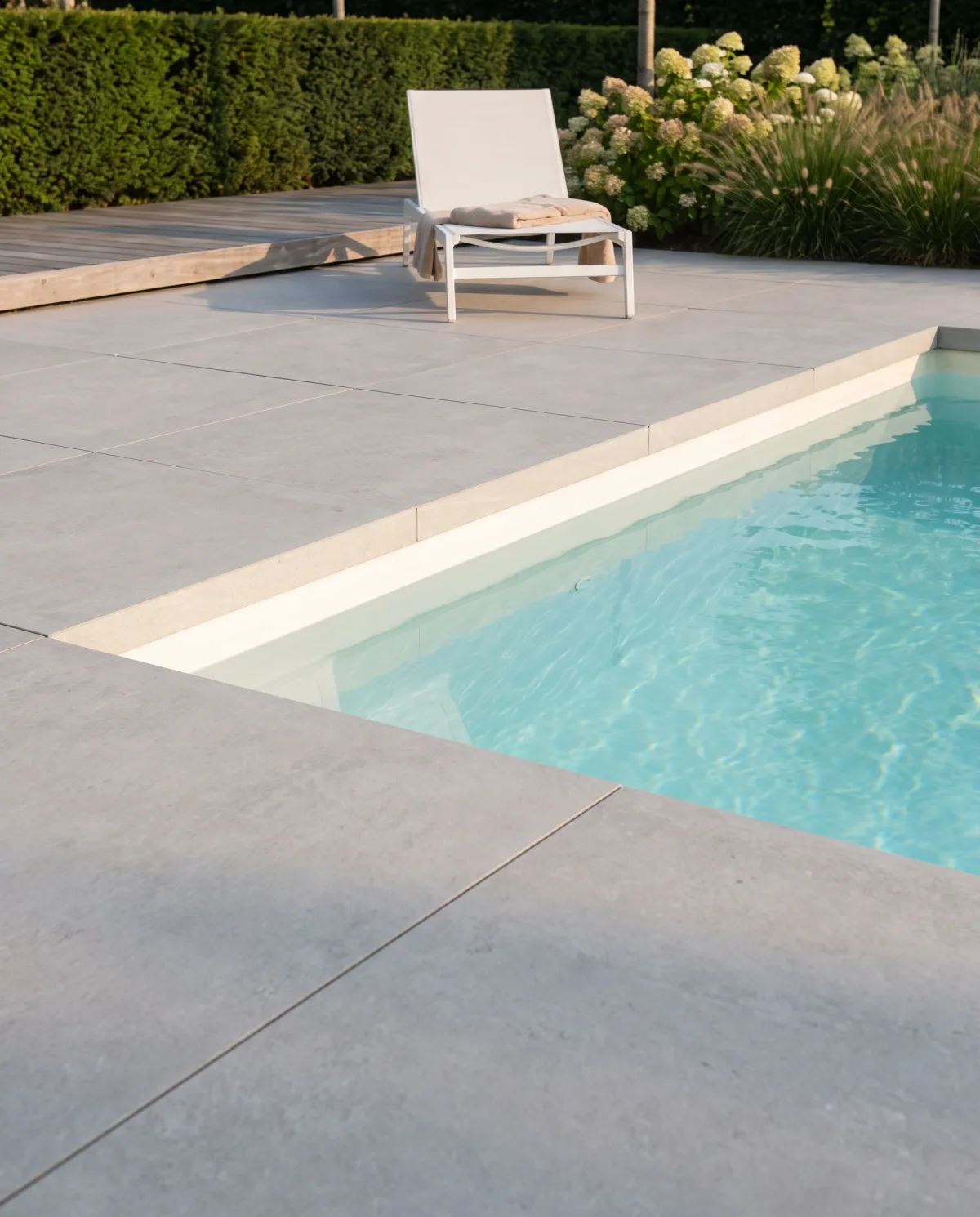 KI-generierte Darstellung: Ruhige Gartenecke am Pool — Rasen, Bepflanzung und heller Plattenbelag treffen auf die Beckenkante