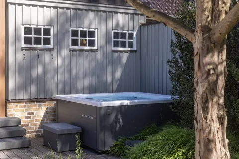 Whirlpool auf einer Holzterrasse vor grauer Holzfassade