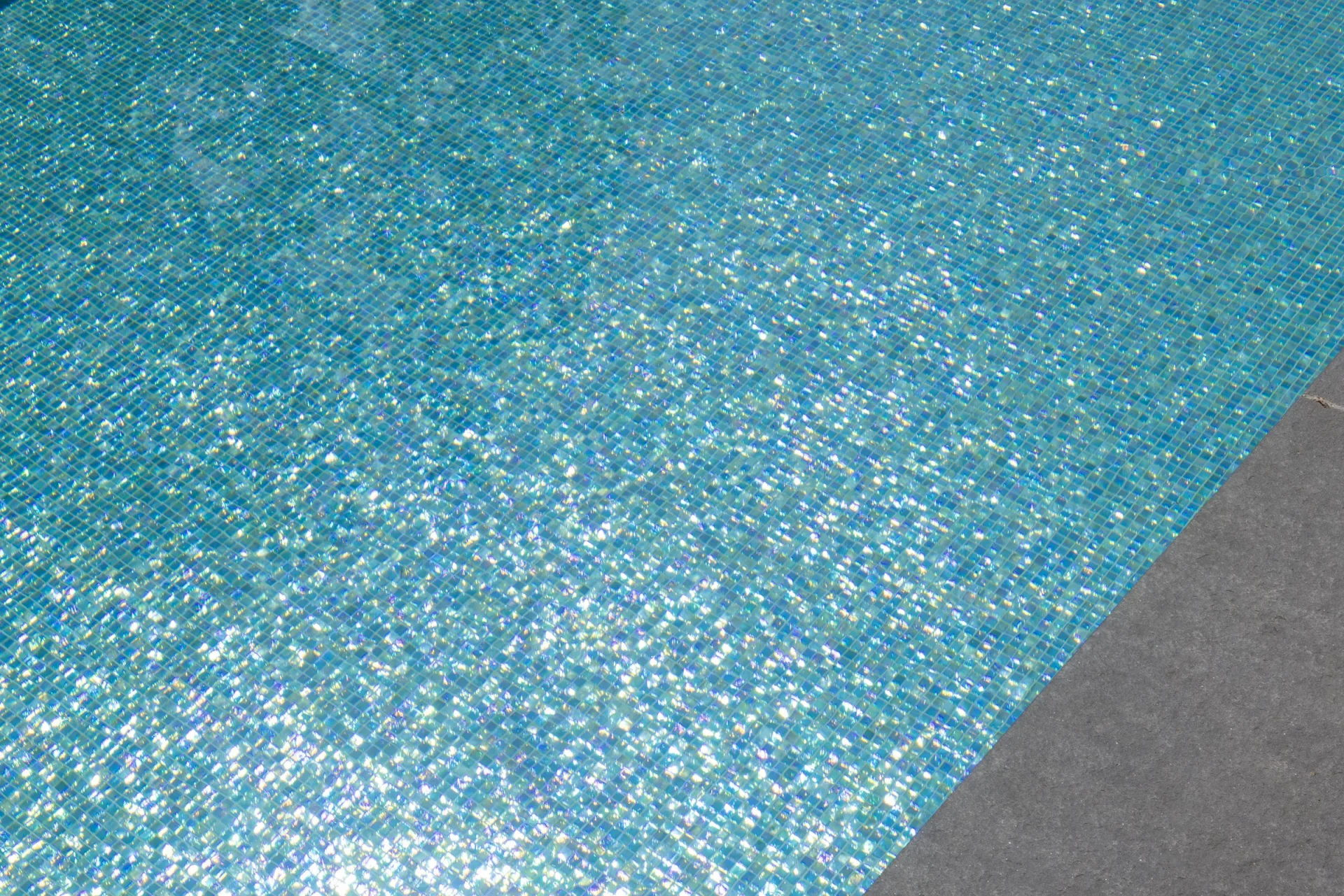 Glasmosaik unter Wasser in Türkis- und Goldtönen, ein Sonnenreflex bricht sich auf der Fläche