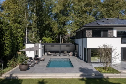 Becken zwischen Terrasse und Rasen vor einem modernen Haus mit Klinker- und Putzfassade