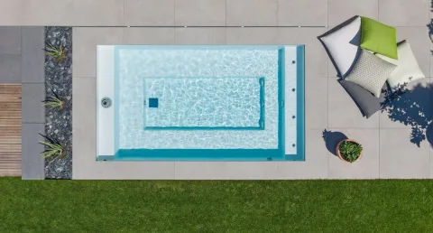 Aufsicht auf ein kleines Becken mit Sitzstufe zwischen Terrasse und Rasen