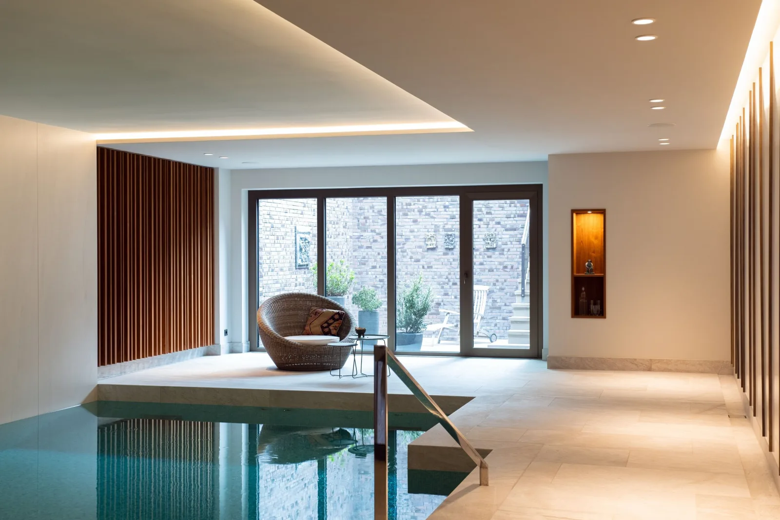 Privater Spa-Raum mit Holzlamellenwand, Sessel und Pool